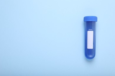 Photo of Test tube with liquid on light blue background, top view and space for text. Kids chemical experiment toy
