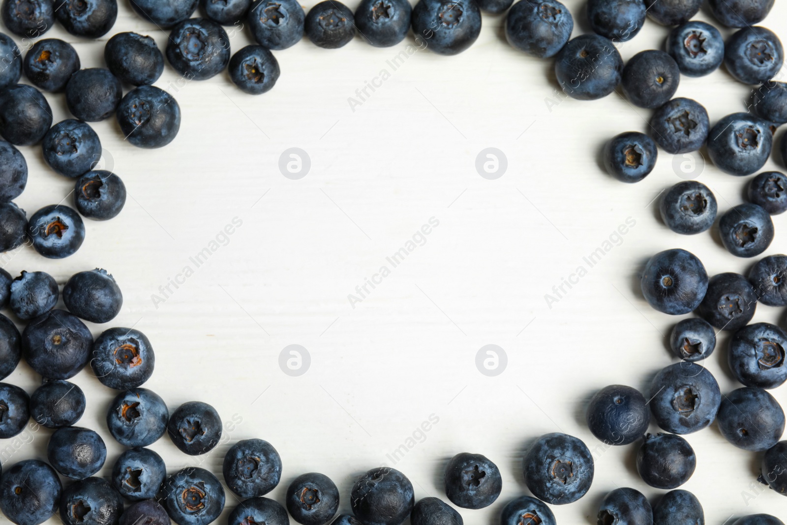 Photo of Frame of fresh ripe blueberries on white wooden table, flat lay. Space for text