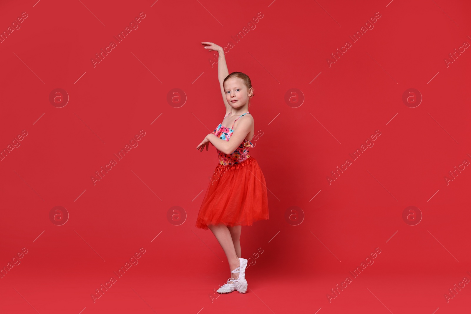 Photo of Cute little girl dancing on red background