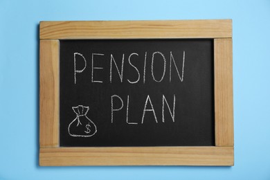 Photo of Chalkboard with phrase Pension Plan on light blue background, top view