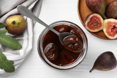 Photo of Jar of tasty sweet jam and fresh figs on white wooden table, flat lay