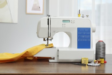 Photo of Sewing machine with fabric and craft accessories on wooden table indoors