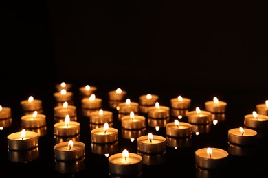 Burning candles on mirror surface in darkness