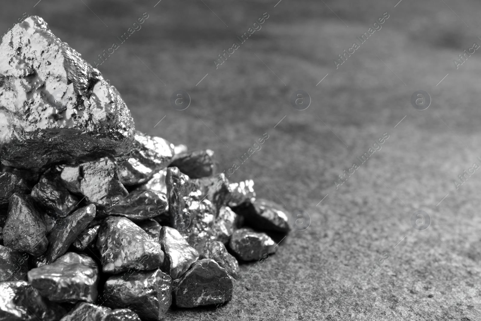 Photo of Pile of silver nuggets on grey textured table, closeup. Space for text