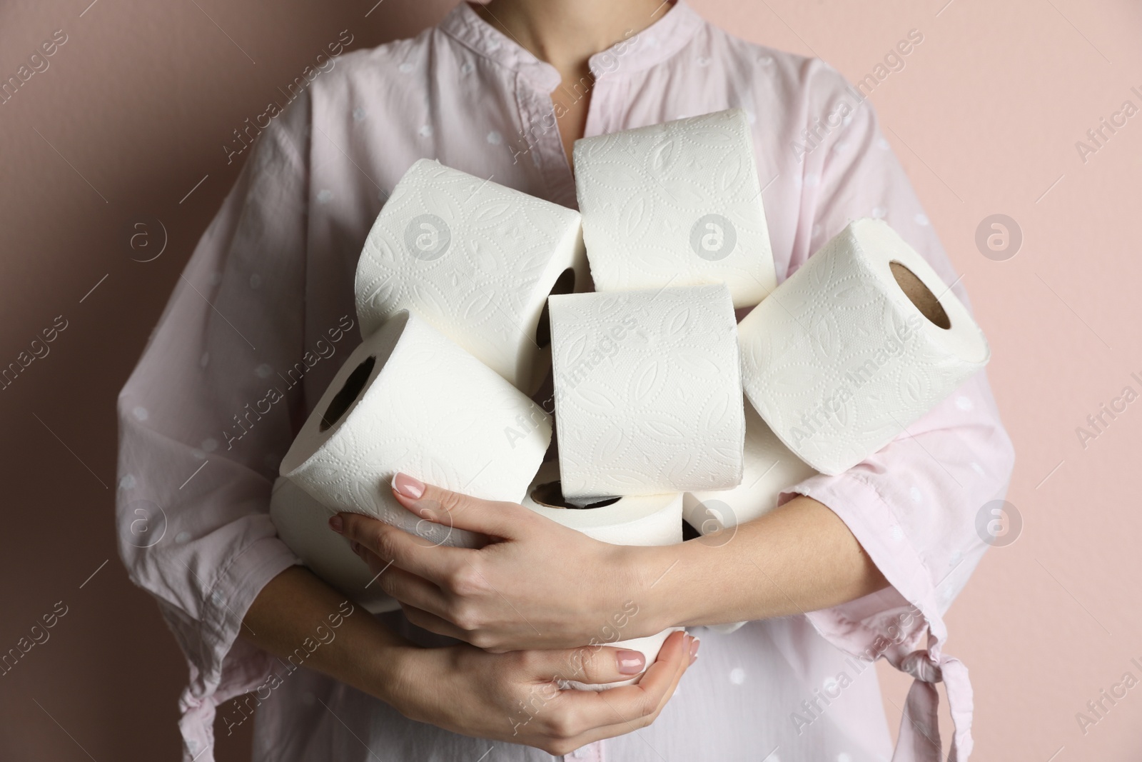 Photo of Woman with heap of toilet paper rolls on pink background, closeup