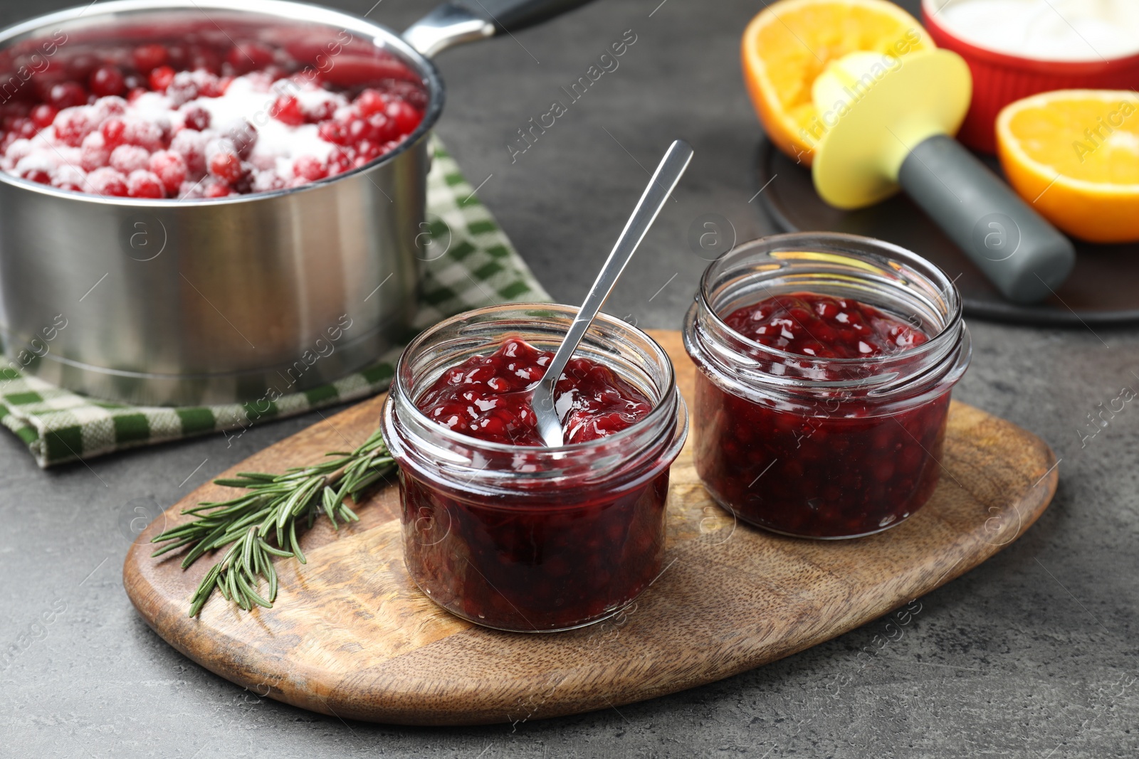 Photo of Fresh cranberry sauce in glass jars served on gray table