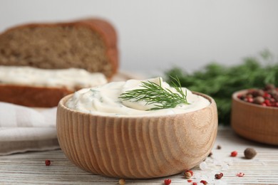 Photo of Tasty creamy dill sauce in bowl on white wooden table, closeup