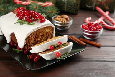 Traditional classic Christmas cake decorated with cranberries and rosemary on wooden table