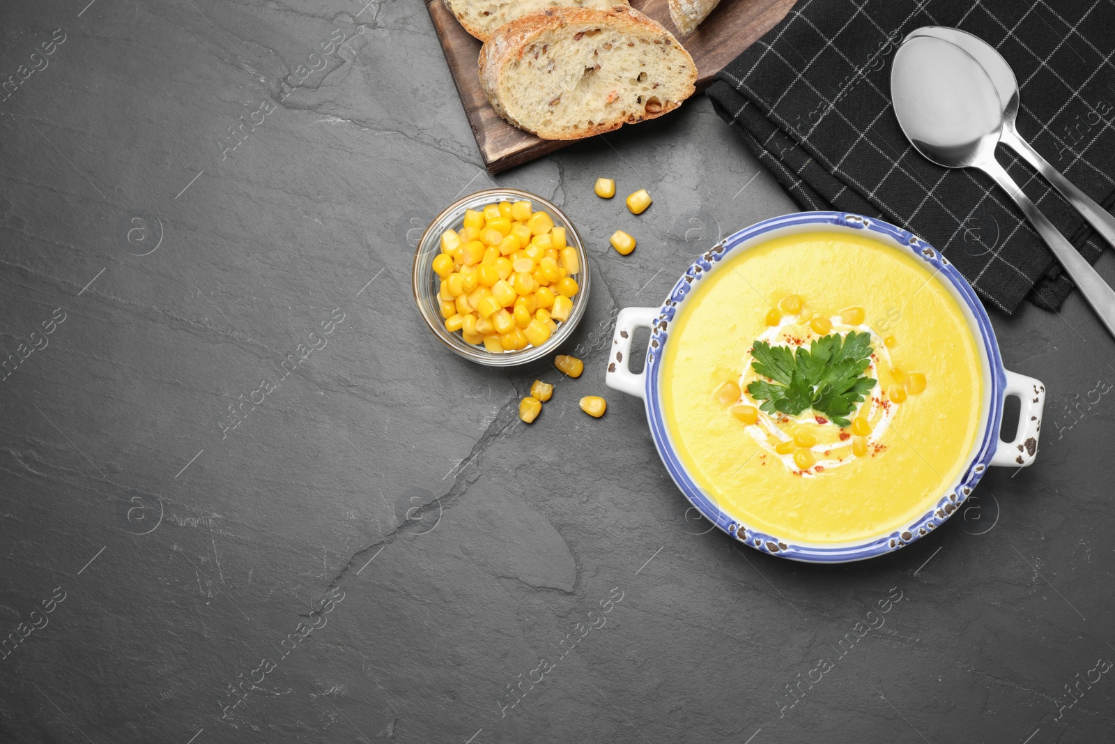 Photo of Delicious creamy corn soup served on black table, flat lay. Space for text