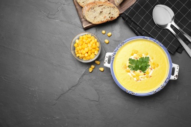 Delicious creamy corn soup served on black table, flat lay. Space for text