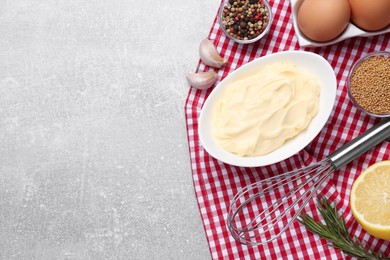 Delicious homemade mayonnaise, spices, whisk and ingredients on grey table, top view. Space for text