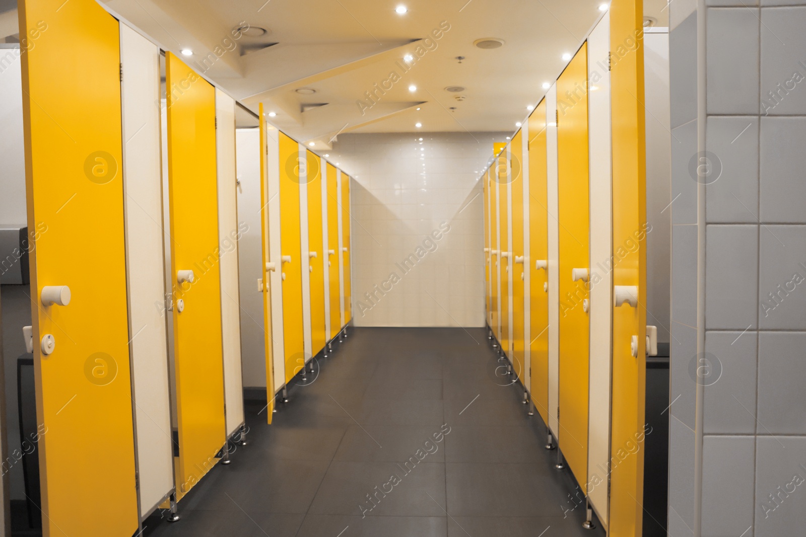 Photo of Public toilet interior with bright yellow stalls