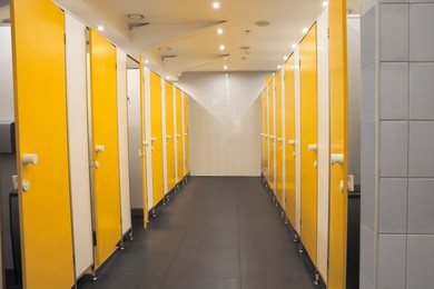 Photo of Public toilet interior with bright yellow stalls