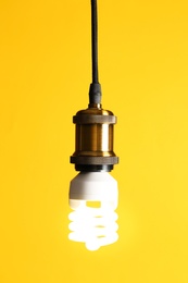 Hanging fluorescent lamp bulb against yellow background