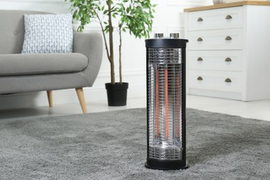 Modern infrared heater on carpet in cozy room