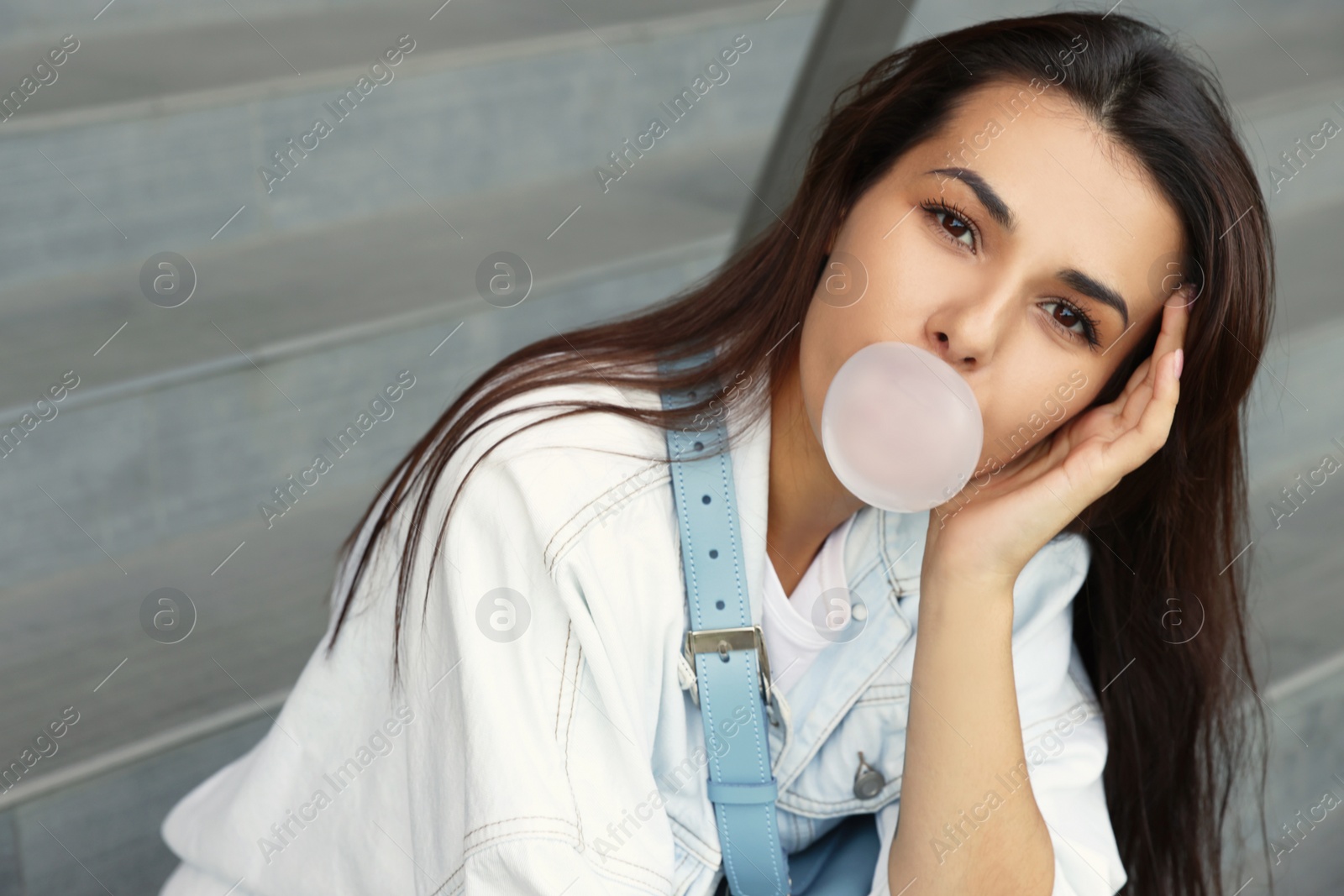 Photo of Stylish woman blowing gum near stairs outdoors