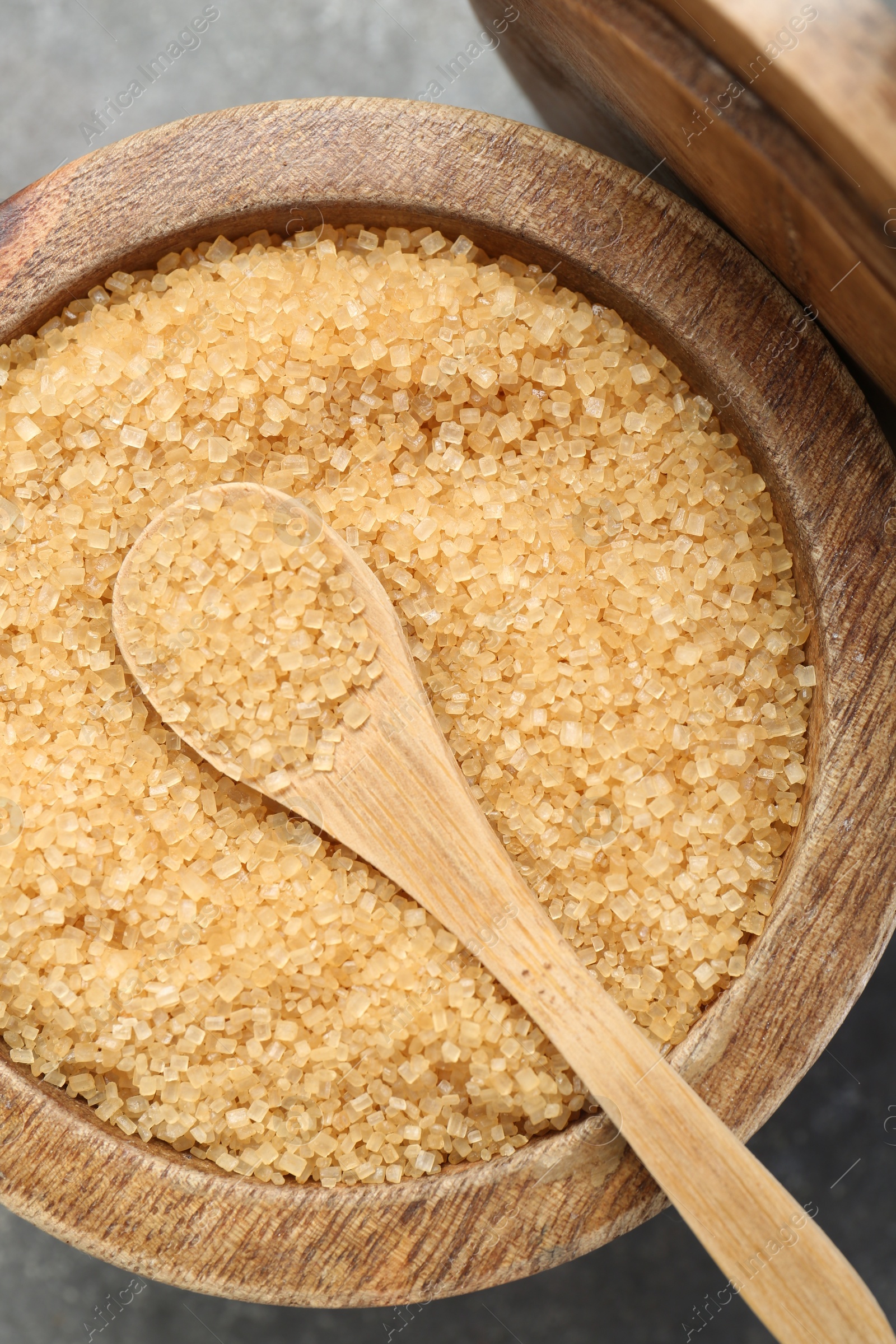 Photo of Brown sugar in bowl and spoon on grey table, top view