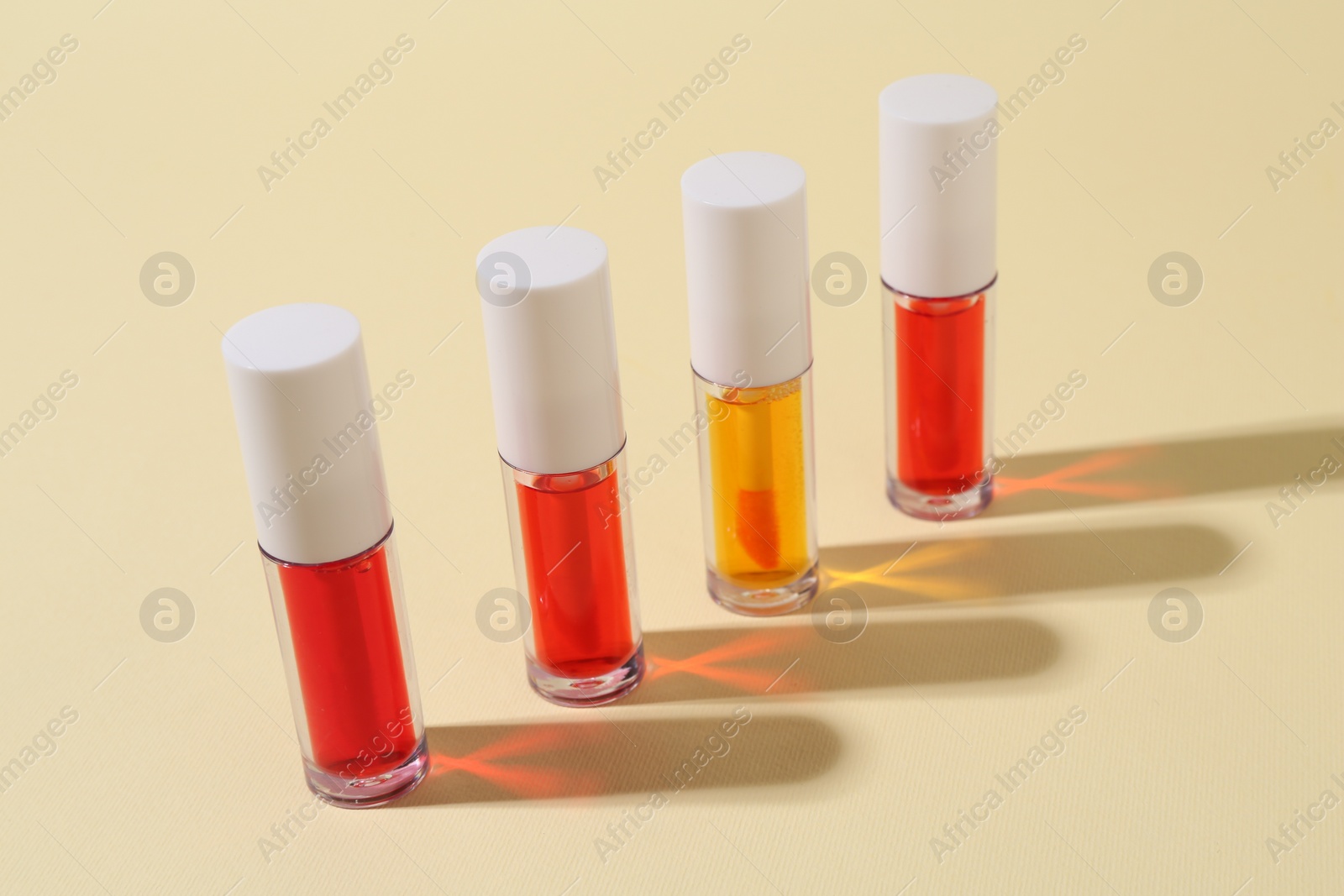Photo of Many bright lip glosses on beige background