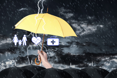 Insurance agent covering illustrations with yellow umbrella during storm