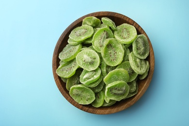 Bowl with slices of kiwi on color background, top view. Dried fruit as healthy food