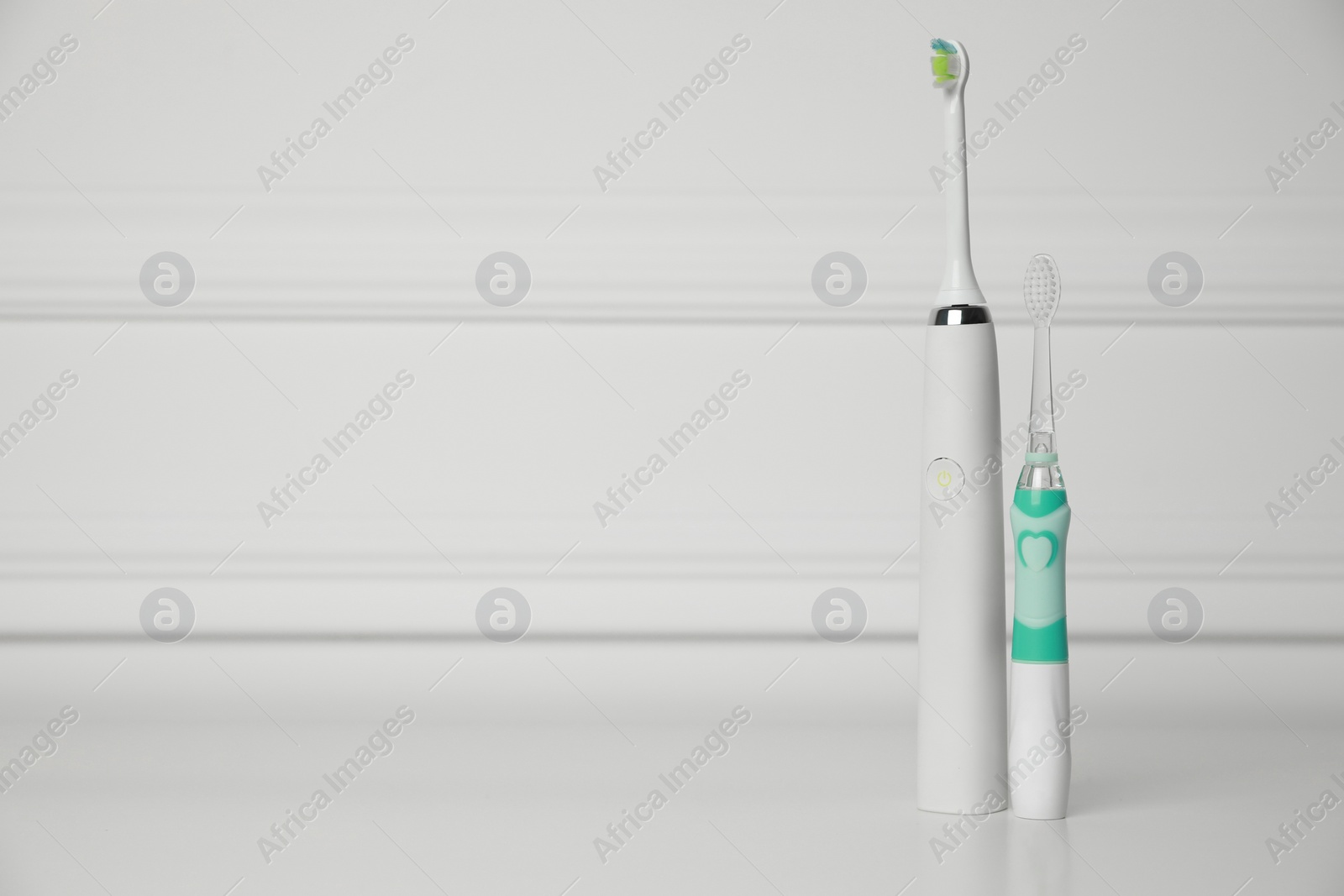 Photo of Electric toothbrushes on white background, space for text