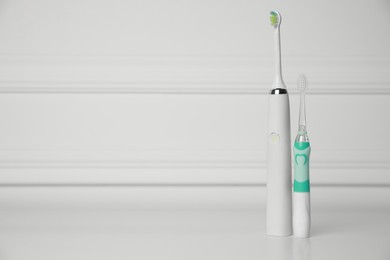 Photo of Electric toothbrushes on white background, space for text