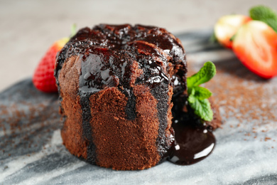 Photo of Delicious warm chocolate lava cake on marble board, closeup