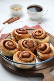 Tasty cinnamon rolls served on white wooden table