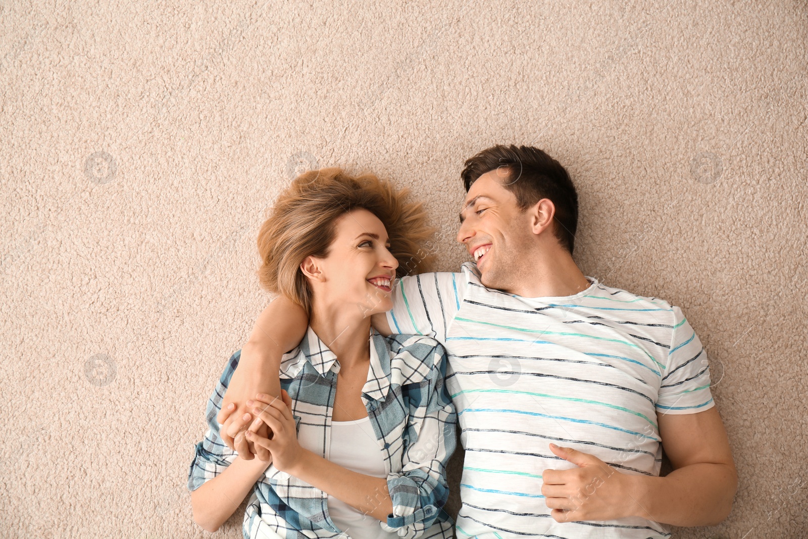 Photo of Lovely young couple lying on cozy carpet at home