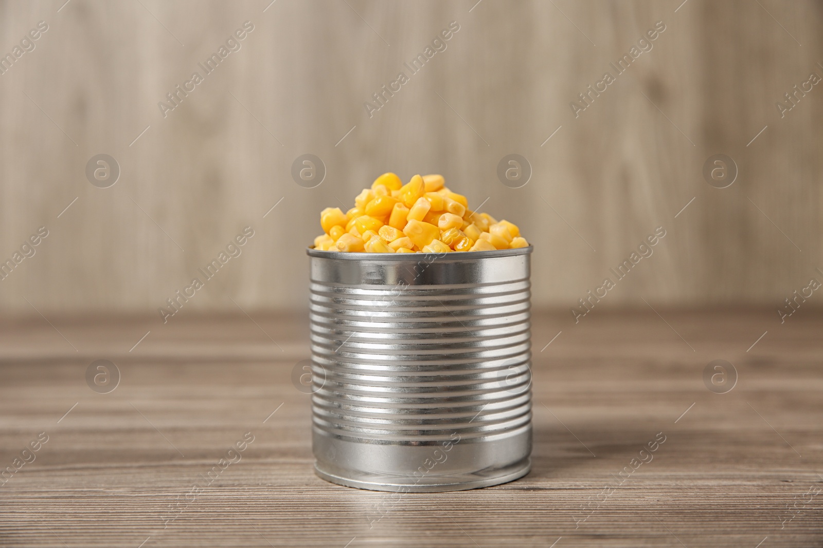 Photo of Open tin can of sweet corn on wooden table