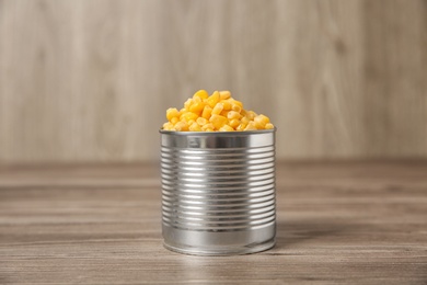Open tin can of sweet corn on wooden table
