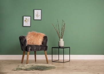 Photo of Armchair with pillow near color wall in room