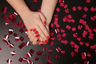 Woman showing red manicure on dark background, top view with space for text. Nail polish trends