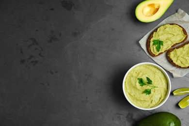 Photo of Flat lay composition with bowl of guacamole made of ripe avocados on grey table. Space for text