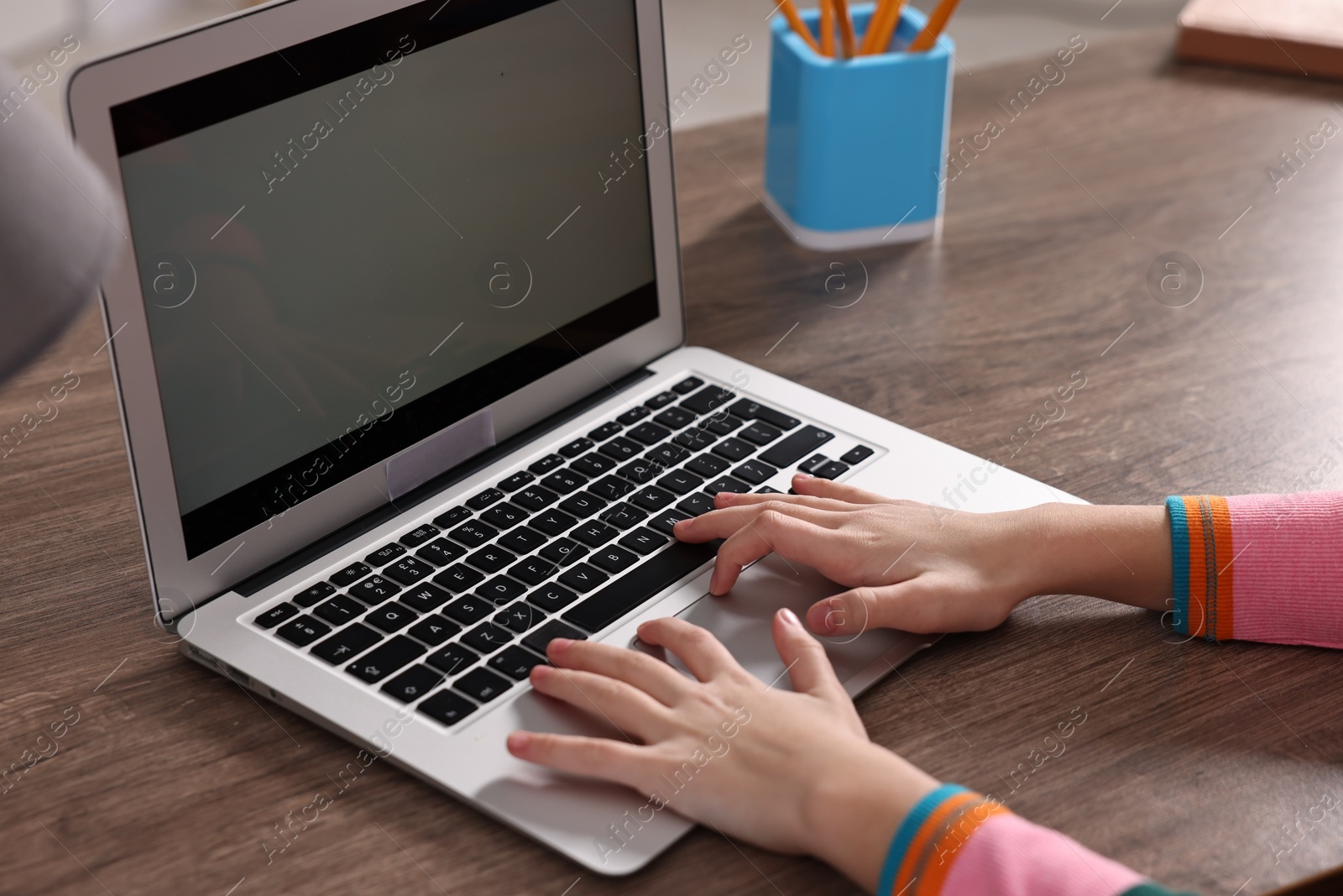 Photo of E-learning. Girl using laptop during online lesson at table indoors, closeup