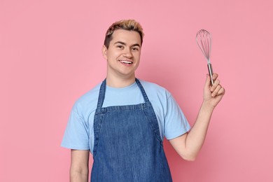 Photo of Portrait of happy confectioner holding whisk on pink background