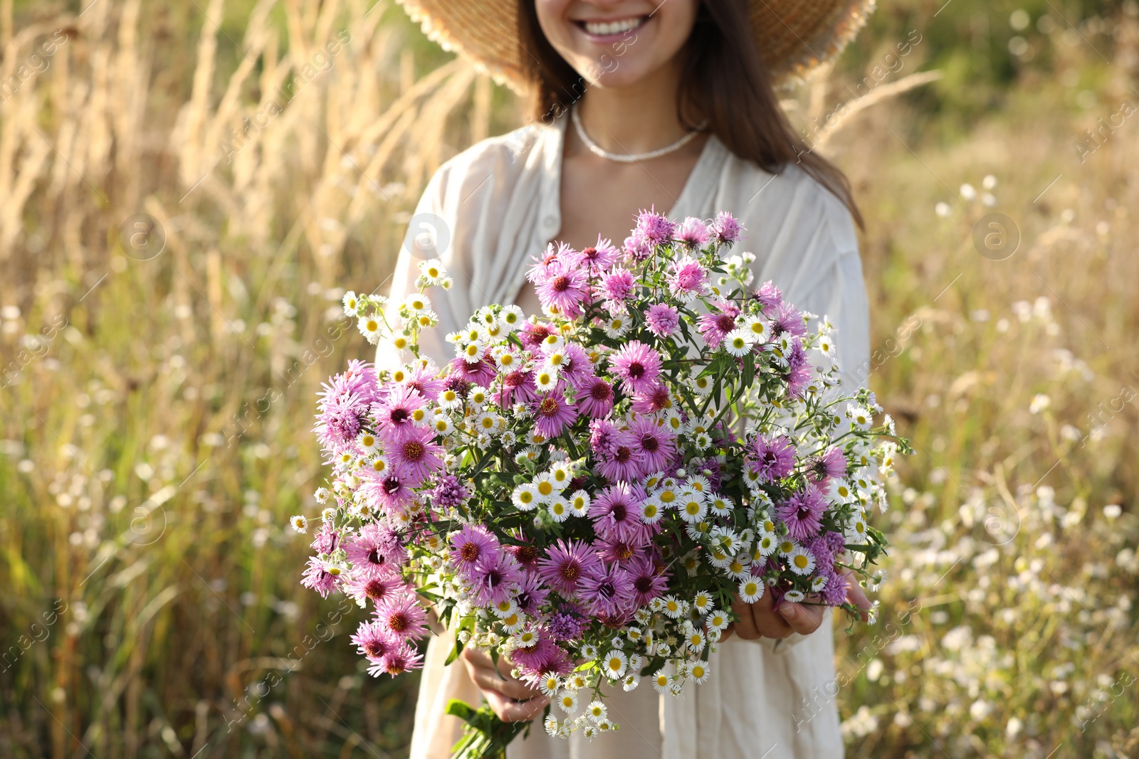 Photo of Woman holding bouquet of beautiful wild flowers outdoors, closeup