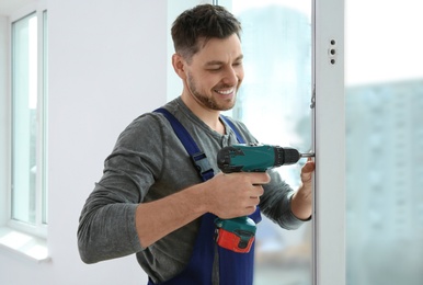 Construction worker using drill while installing window indoors