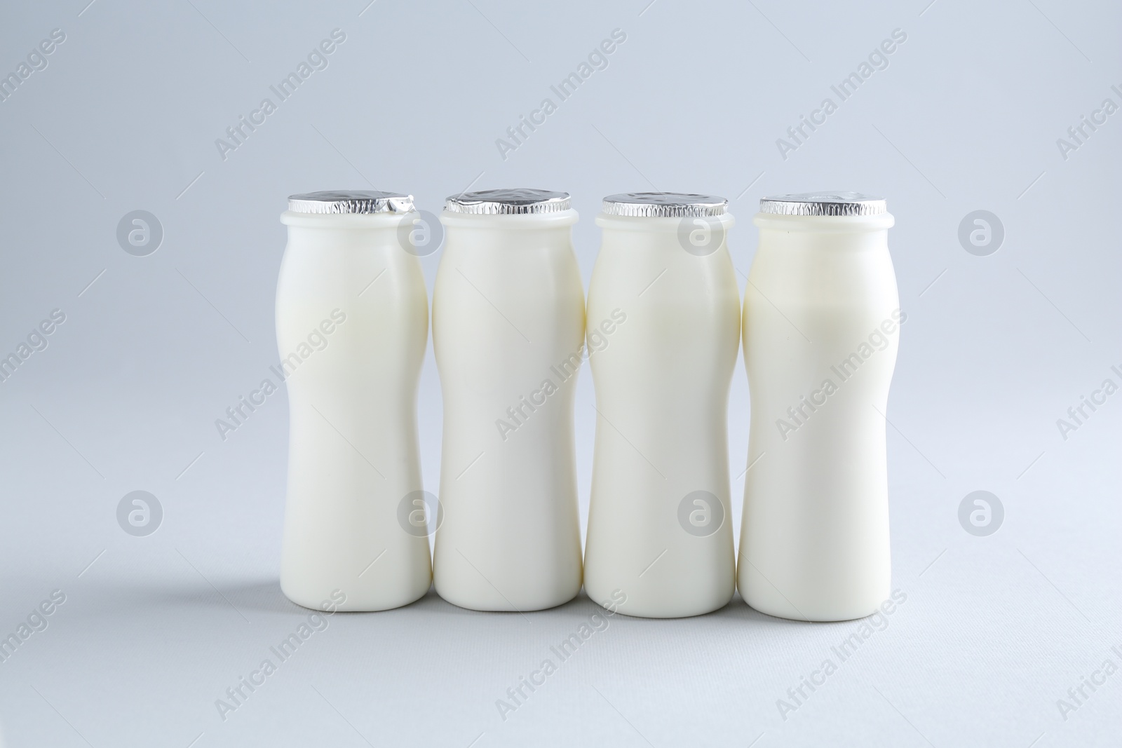 Photo of Tasty yogurt in bottles on light grey background