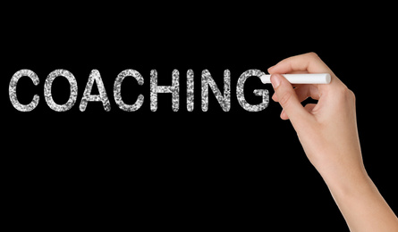 Image of Business or life trainer writing word Coaching on blackboard, closeup