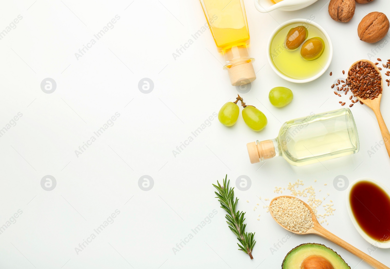 Photo of Vegetable fats. Different oils in glass bottles and ingredients on white table, flat lay. Space for text