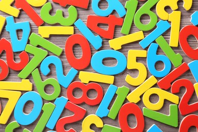 Photo of Colorful numbers on wooden school desk, top view