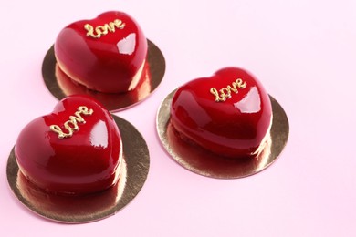 Photo of St. Valentine's Day. Delicious heart shaped cakes on light pink background, closeup