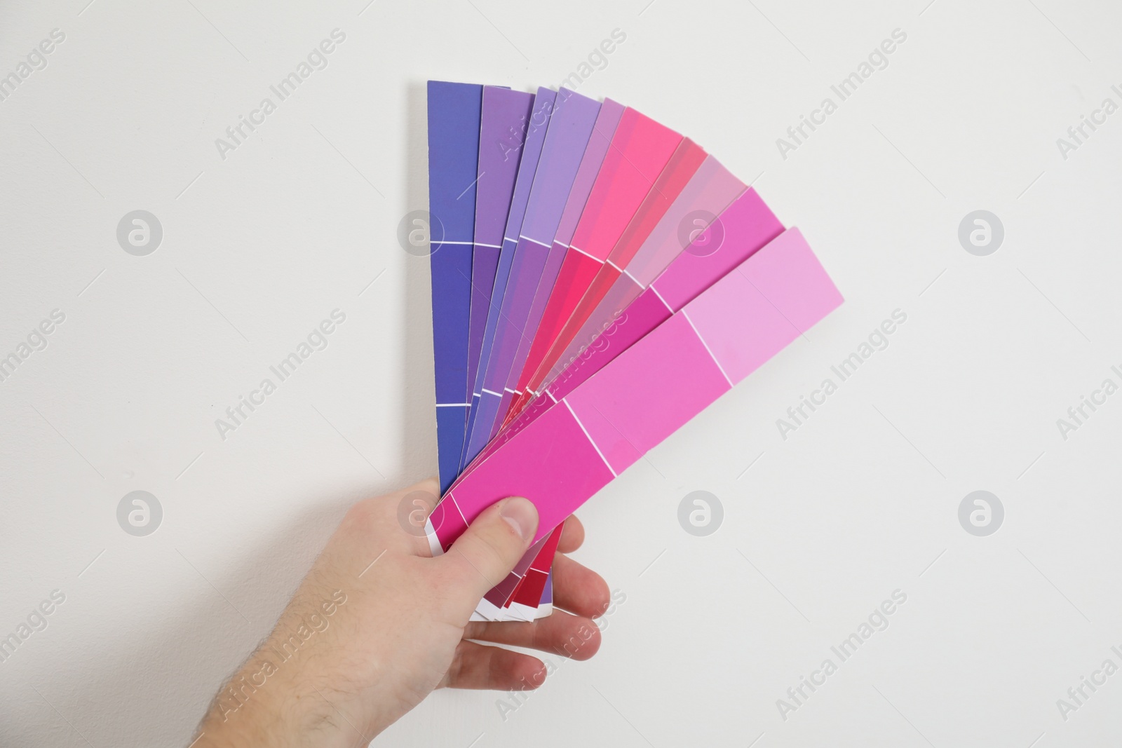 Photo of Man with palette choosing color for painting wall indoors, closeup. Interior design