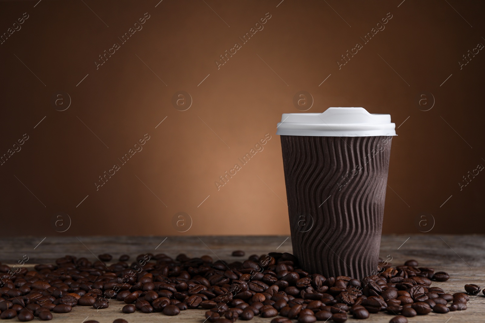 Photo of Coffee to go. Paper cup and roasted beans on wooden table, space for text