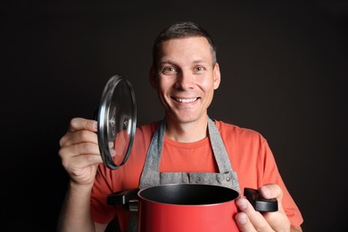 Photo of Happy man with cooking pot on brown background