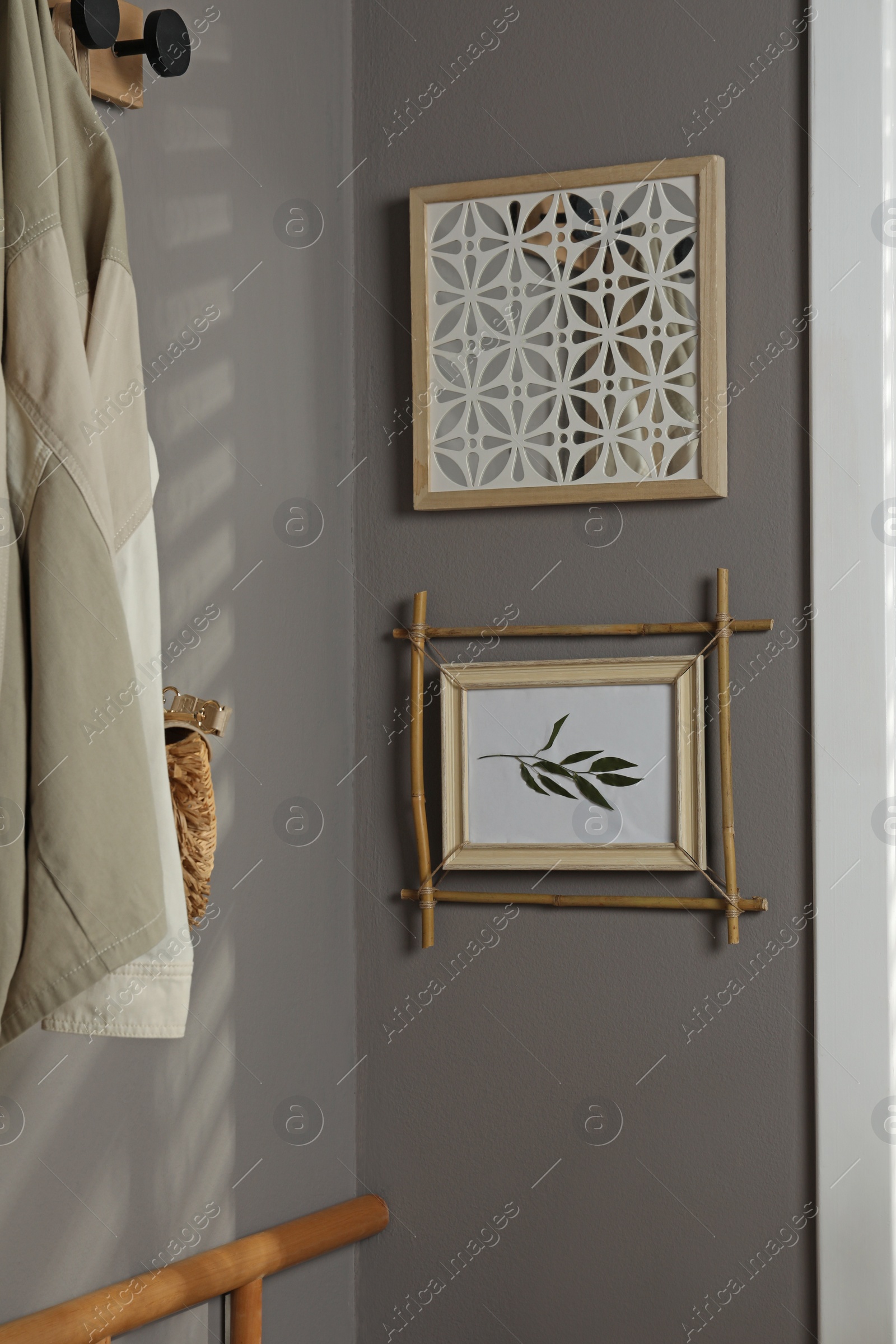 Photo of Stylish hallway interior with bamboo frame on grey wall