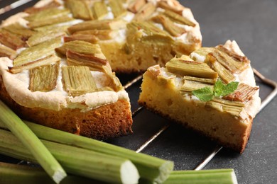 Photo of Freshly baked rhubarb pie and stalks on black table, closeup