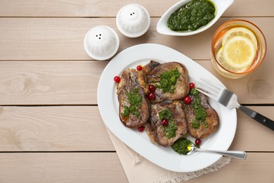 Tasty beef tongue pieces, salsa verde and berries on beige wooden table, flat lay. Space for text