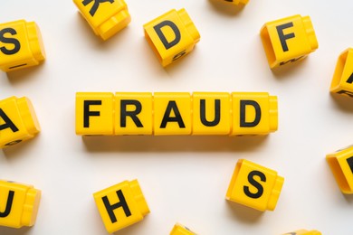 Photo of Word Fraud of yellow cubes with letters on white background, top view